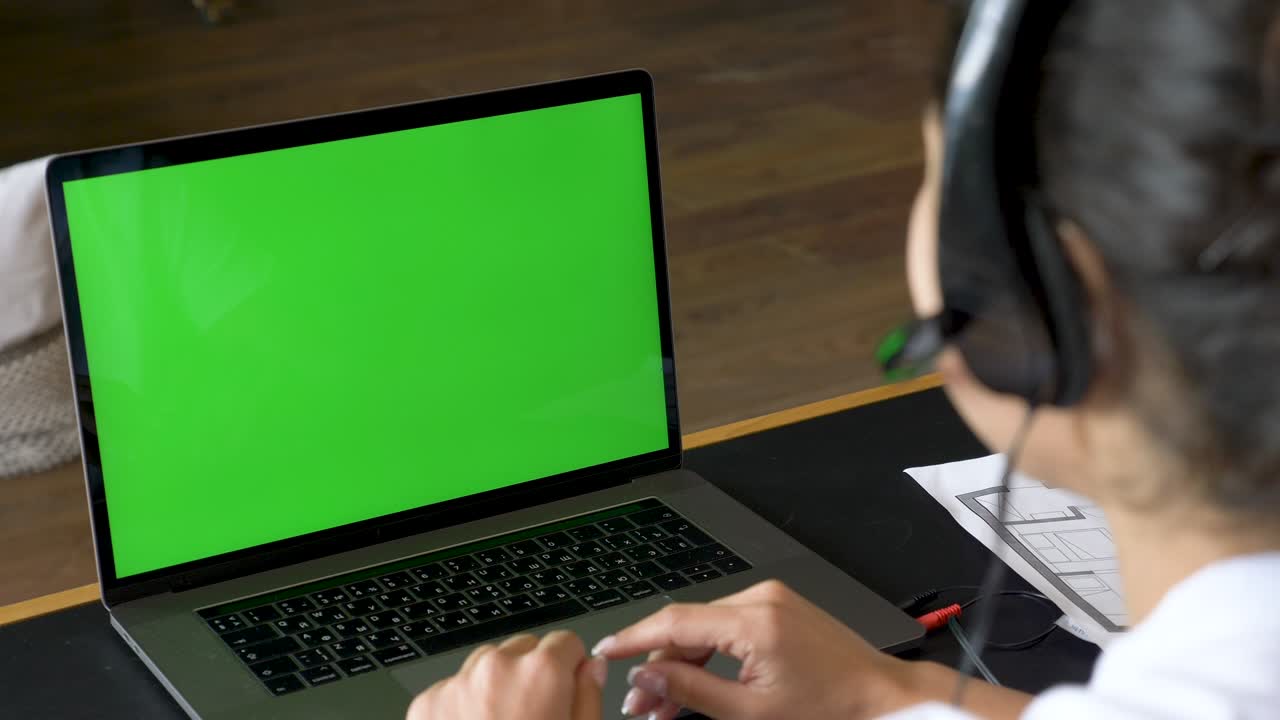 primer plano de una joven india que se comunica con un cliente usando una computadora portátil con una pantalla verde trabajando en una conferencia en línea, entrenando con personas, usando una ordenador. habitación brillante en la silla de la casa