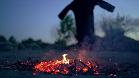 embers of fire and scary witch outdoors. death in black costume goes away from fire. halloween concept.