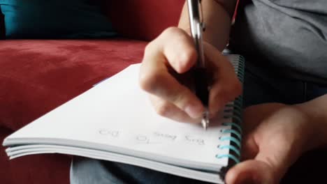 male with a partially amputated index finger on his right hand sat down holding a pen and pad  writing a to do list.