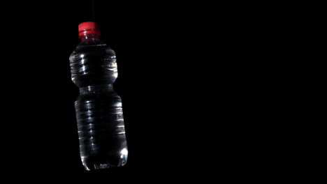 plastikflasche, die sich auf schwarzer oberfläche dreht