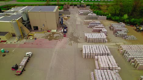 aerial view of a busy industrial shipping yard with forklifts loading flatbed semi-truck