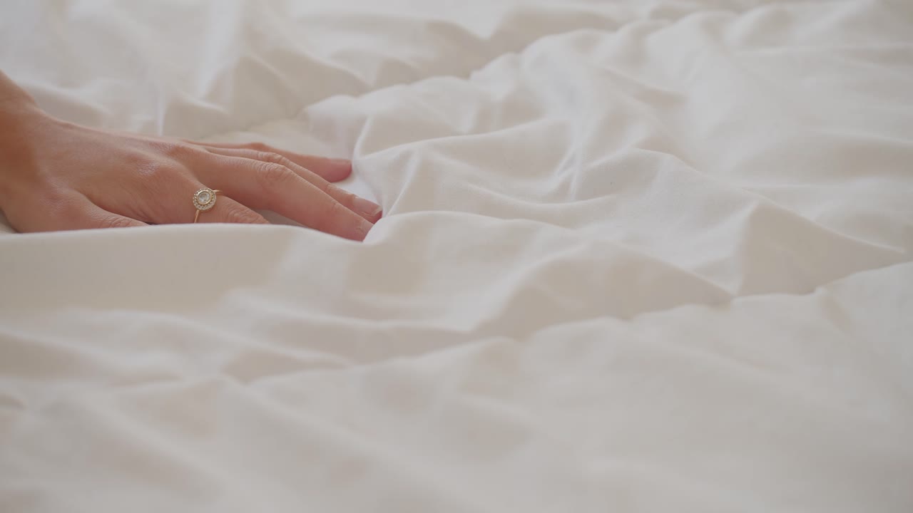 부드러운 흰색 커버 이불을 만지는 여성의 손