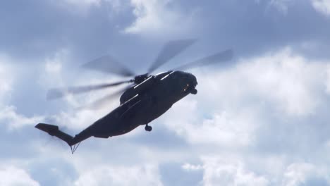 a black military helicopter flys low and sideways at an air show in berlin