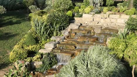 hermosa cascada de jardín con escalones de piedra y vegetación exuberante