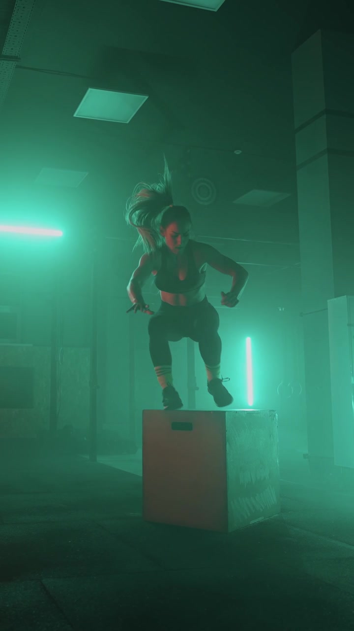 Donna atletica esegue un allenamento intenso con burpees e box jumps in palestra.