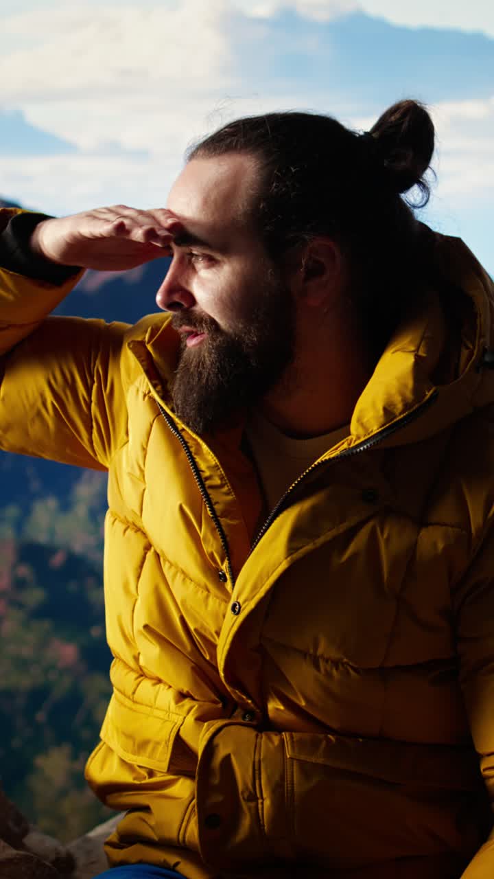 Uomo con piumino giallo che ammira un panorama montano