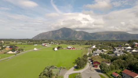 view of rural houses with beautiful green farm landscape and mountain in distanse at hustad, norway