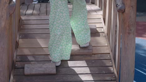 child climbing wooden playground bridge