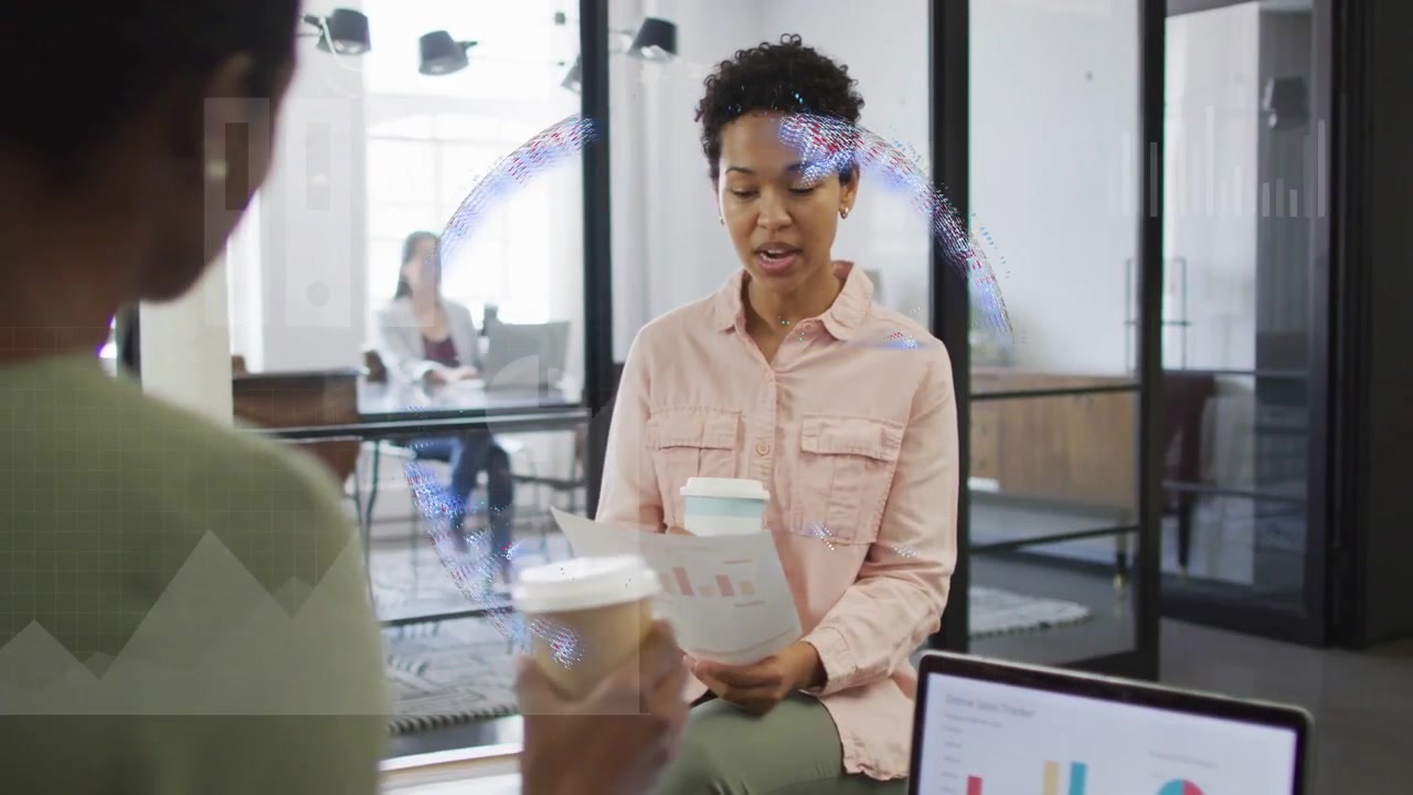 Seated woman reading charts, accepting cup from peer, reviewing business as globe overlaying laptop