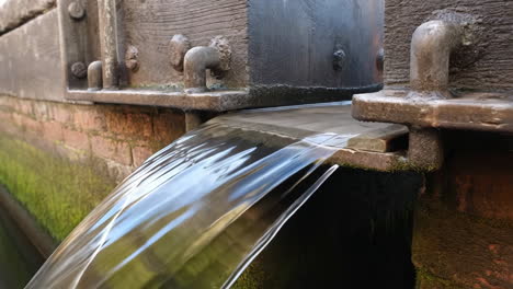 water flowing from a rustic wooden sluice gate