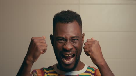 portrait of african american man wearing kente fabric shirt excitingly celebrating