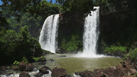 overhanging rocky cliff with pouring waterfall streams splashing into hidden pool, amazing scenic views in iguacu falls, argentina, south america, hiding in tall grown beautiful jungle landscape