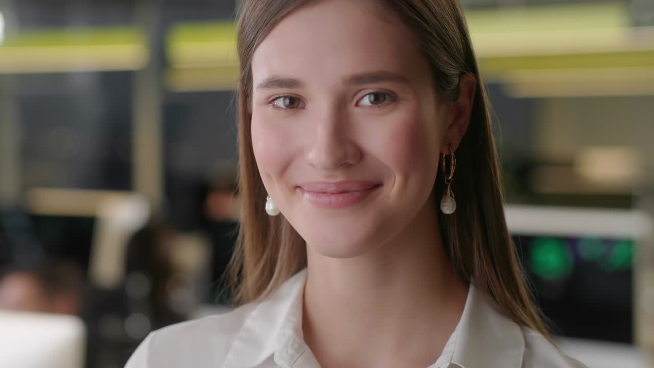 Front view of beautiful young Woman professional Wearing White Shirt. Portrait of young female office manager looking to camera and having good mood. Blurred office background