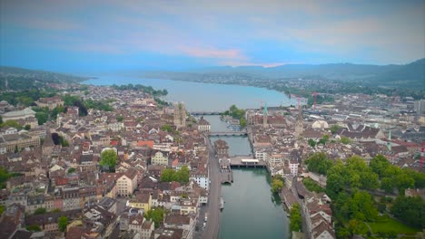 Luftstoß-In-Zürich,-Schweiz,-Gründungsaufnahme,-Kirche,-Europa,-Wasser,-Fluss,-Bach,-Statue,-Brücke,-Europa,-Kirchturm,-Gehweg,-Menschen,-Stadtarchitektur,-4K,-Touristenziel,-Ansicht,-Schweizer-Stadt