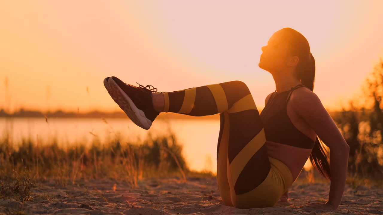 Fit healthy woman stretching on yoga mat on beach seasidedoing exercise abdominal crunchestraining and lifestyle. Sit ups training on dock beach in sunset