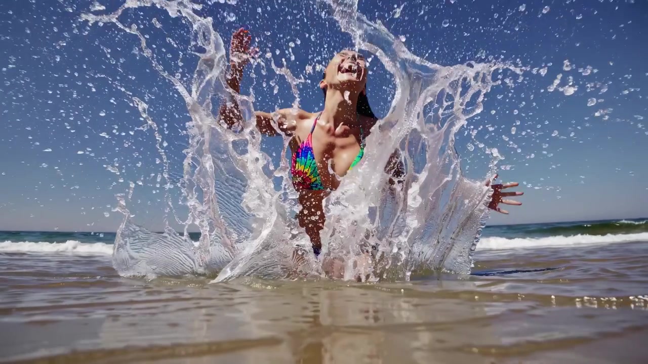 Joyful Woman in Bikini Splashing Water at the Beach in Slow Motion