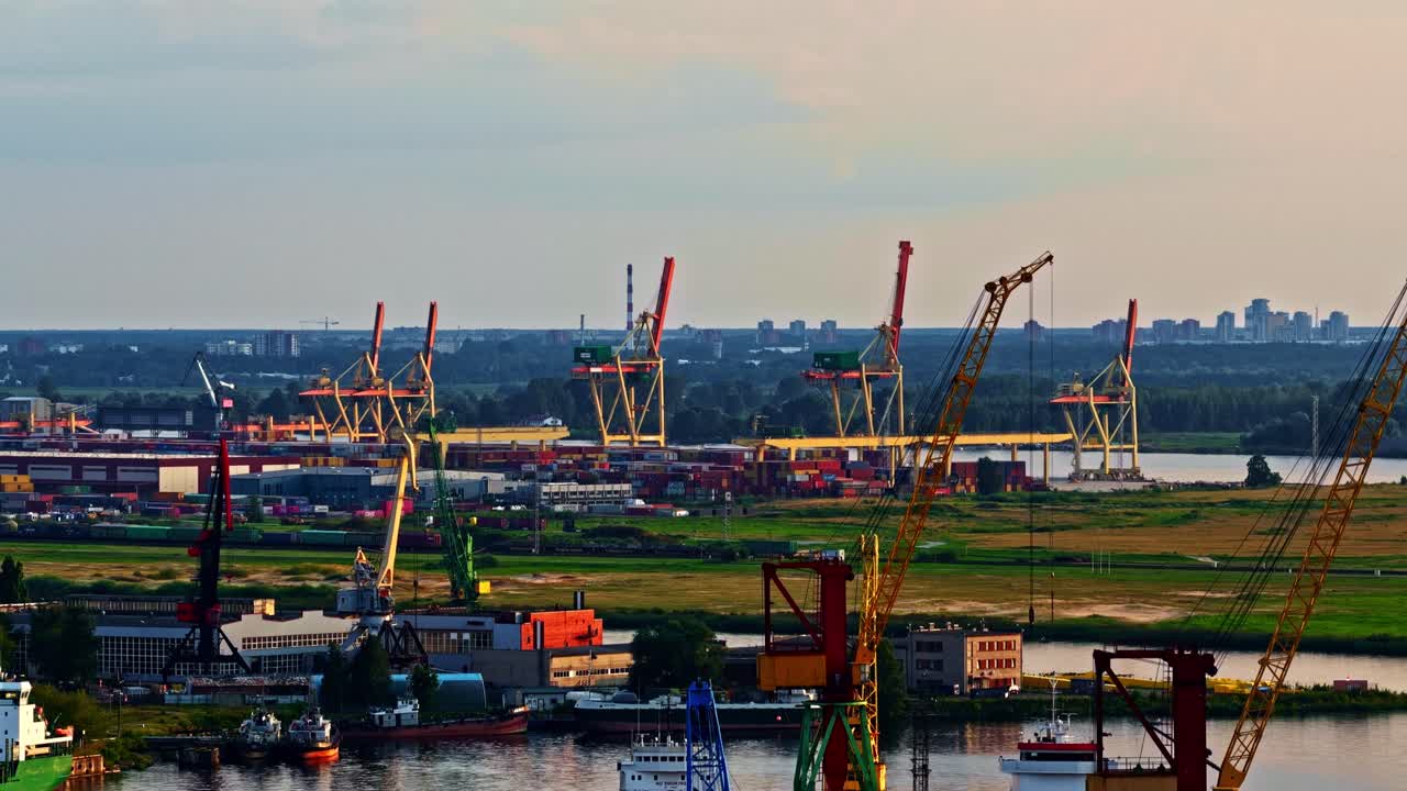 Busy industrial port with cranes and containers at sunset