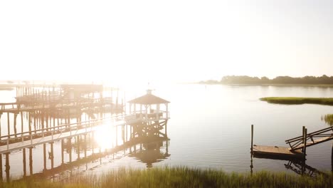 peaceful morning sunrise drone right pan from pier, waterway, houses, and marsh at trails end park in wilmington north carolina