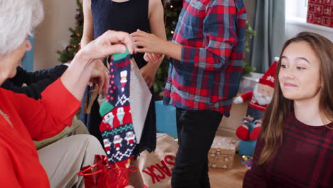 grandchildren giving gifts to grandparents as they celebrate christmas day at home together