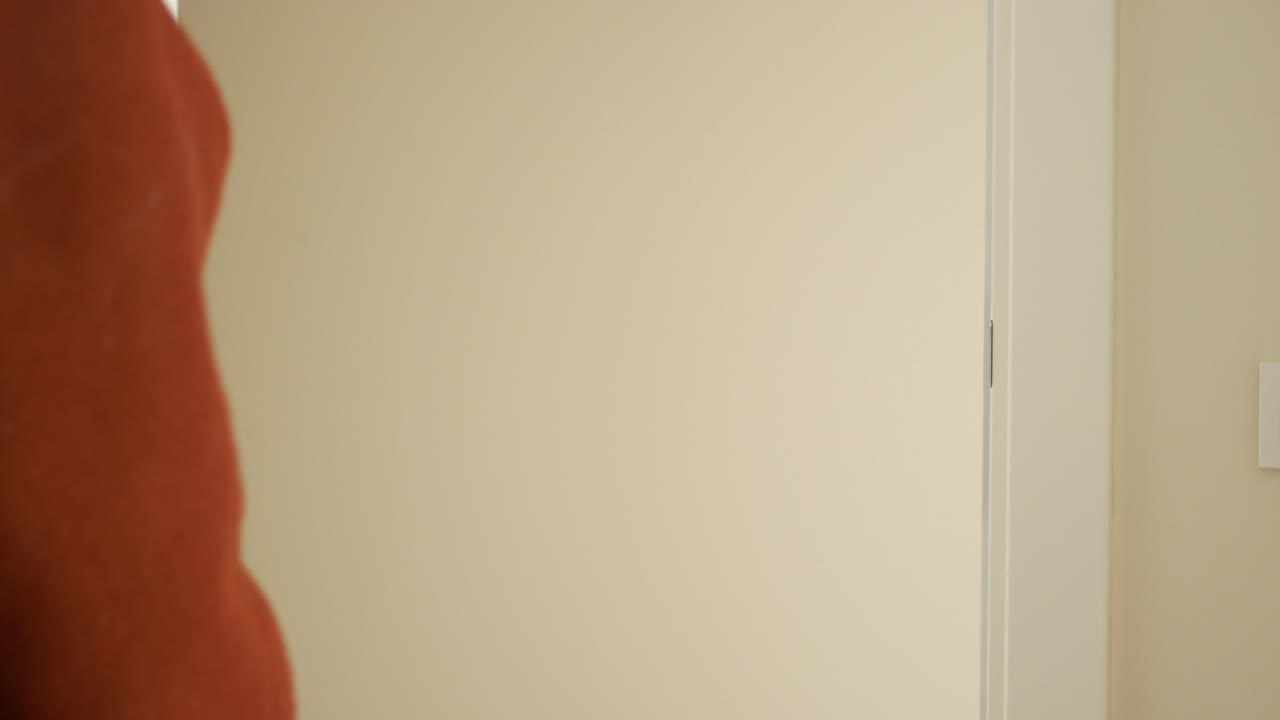 una persona con un abrigo marrón abriendo una puerta blanca