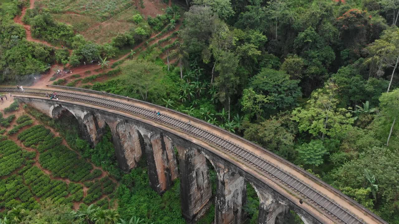 Vista aérea de un tren cruzando el Puente de los Nueve Arcos con personas y plantaciones de té en Ella Badulla, Sri Lanka