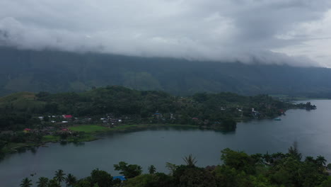 Aerial-drone-flyover-on-a-rainy-day-of-a-lake-side-village-on-Samosir-Island-on-Lake-Toba-in-North-Sumatra,-Indonesia