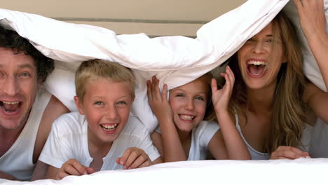 una familia linda escondiéndose en su cama.