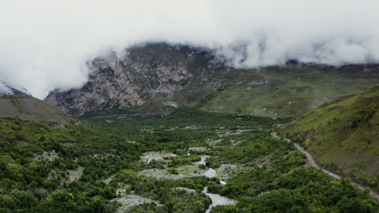 valle de montaña brumosa con río y bosque