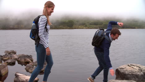 couple on a walk taking a break by the edge of a lake