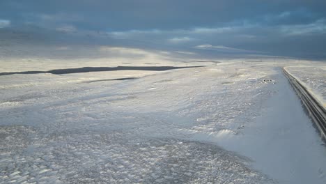 snowy tundra terrain on highway road in iceland during winter - aerial