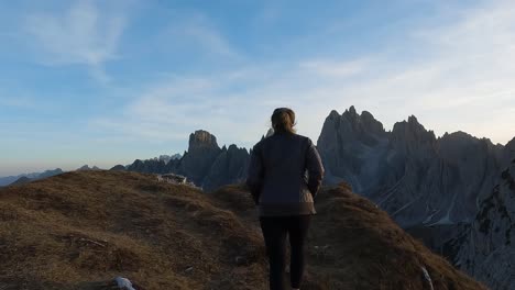 suave luz matinal disfrutada por una mujer caminando a través de los dolomitas de italia para ver picos de montañas épicos