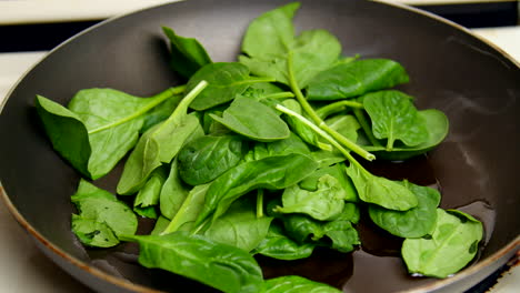 baby spinach is put into a pan and stirred