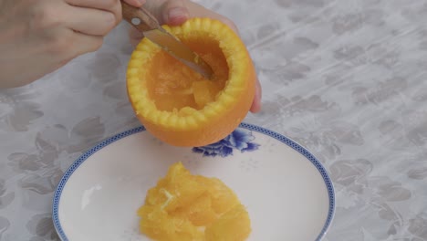 sacar la pulpa de la fruta de la naranja del cuerpo de la piel de la naranja cortada artísticamente en el plato