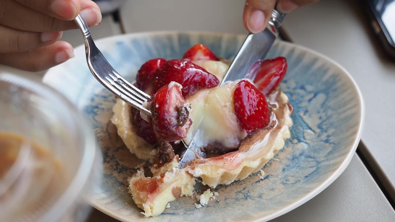 Primo piano di mani che tagliano e mangiano una deliziosa crostata di fragole