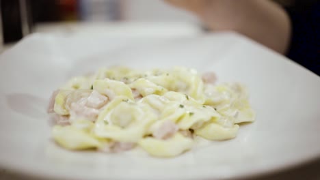 woman putting grated italian cheese on a pasta dish in slowmotion