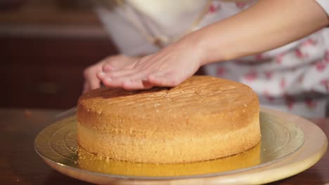 woman leveling a cake layer in the kitchen