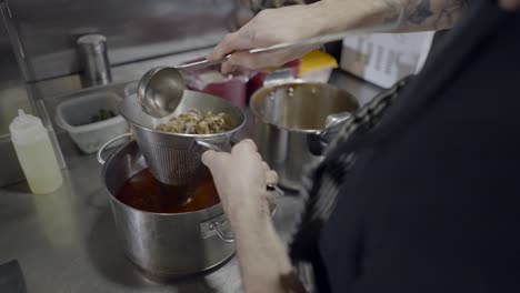 chef straining food in a kitchen