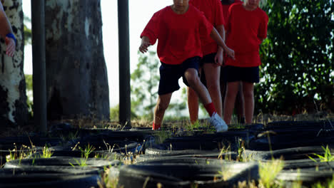 Niños-Corriendo-Sobre-Neumáticos-Durante-El-Entrenamiento-De-Carrera-De-Obstáculos