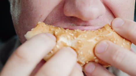 a hungry man eagerly eats a hamburger only his mouth is visible in the frame