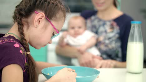 niña desayunando con madre y bebé. niño almorzando en la cocina.