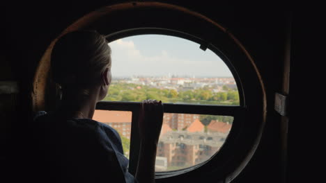 silueta de una mujer mirando en una ventana redonda en los tejados de la ciudad de copenhague en dinamarca