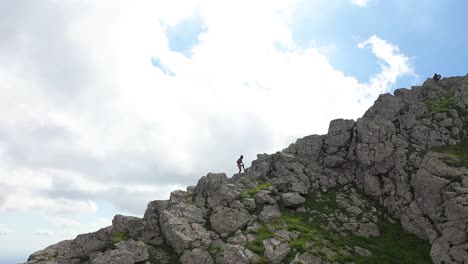 a local black man is hiking up the mountain and the boulders in a very strong and fast tempo