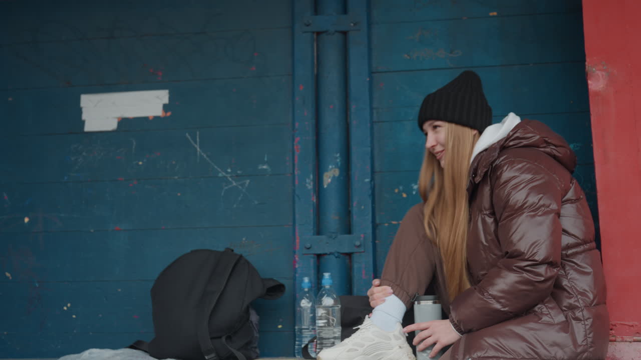 movimiento enérgico en un entorno tranquilo, felicidad espontánea mostrada en un ambiente sereno, una mujer exuberante baila con entusiasmo en un paisaje invernal apacible junto a una pared pintada de colores vivos