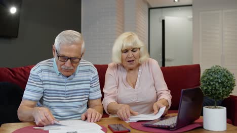 Una-Pareja-De-Ancianos-Estresada-Discute-Las-Facturas-De-Tenencia-De-Deuda-Bancaria-Impagas,-Hace-Trámites-Y-Planifica-El-Presupuesto