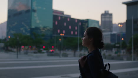young business woman intern waiting on urban city street looking pensive thinking enjoying calm evening wearing backpack