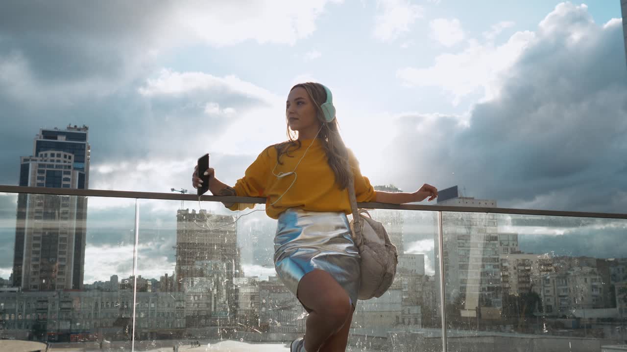 retrato de una joven linda y atractiva en las calles de la ciudad urbana fondo escuchando música con auriculares. mujer con blusa amarilla y falda plateada
