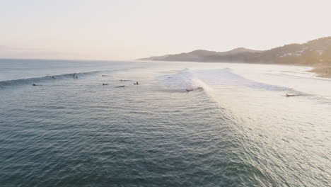 aéreo mientras los surfistas reman durante el hermoso amanecer en la costa tropical, 4k