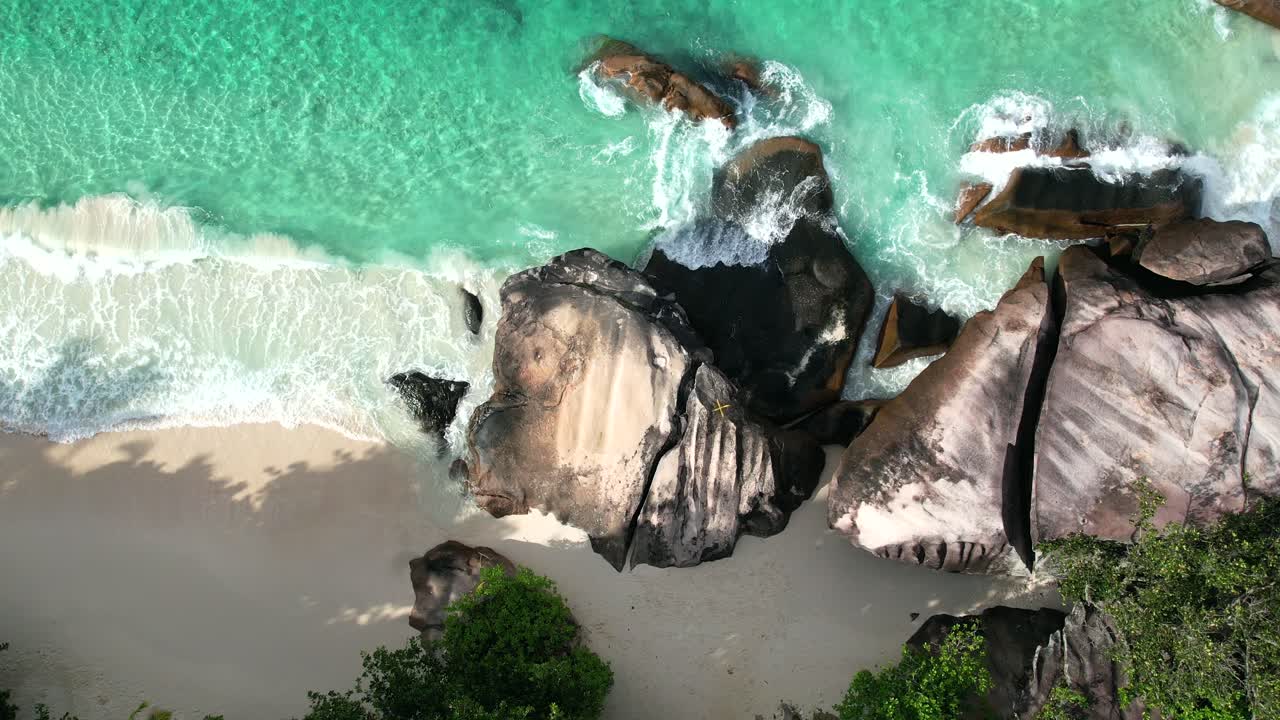 Ripresa aerea con drone di spiaggia di sabbia bianca, grande roccia di granito, alberi e onde che si infrangono sulla riva, Mahé, Seychelles 60 fps 2
