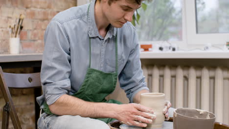 hands of a clerk modeling ceramic piece on a potter wheel in a workshop