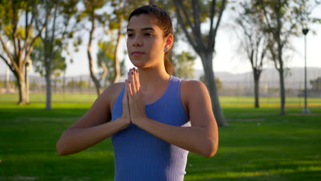 Eine-Schöne-Junge-Hispanische-Yogi-Frau,-Die-Bei-Sonnenaufgang-In-Einer-Einbeinigen-Gebetshände-Im-Park-Meditiert